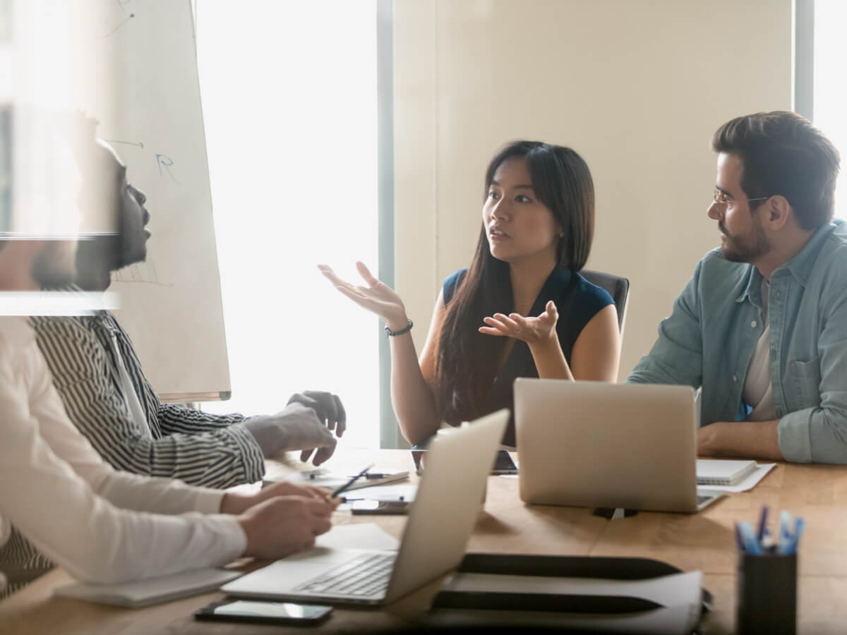 Couple sits at a table with their lawyer, having a discussion over some laptops