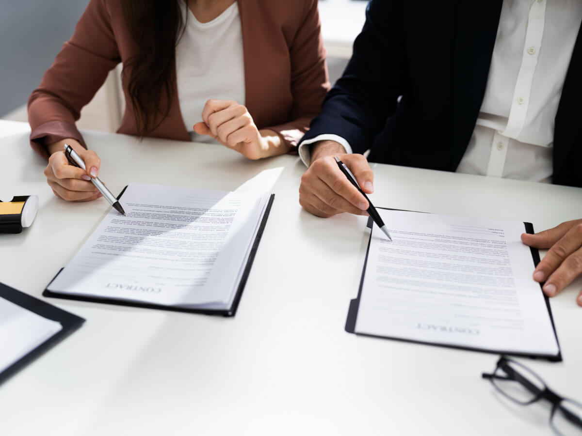 Two people signing legal documents.