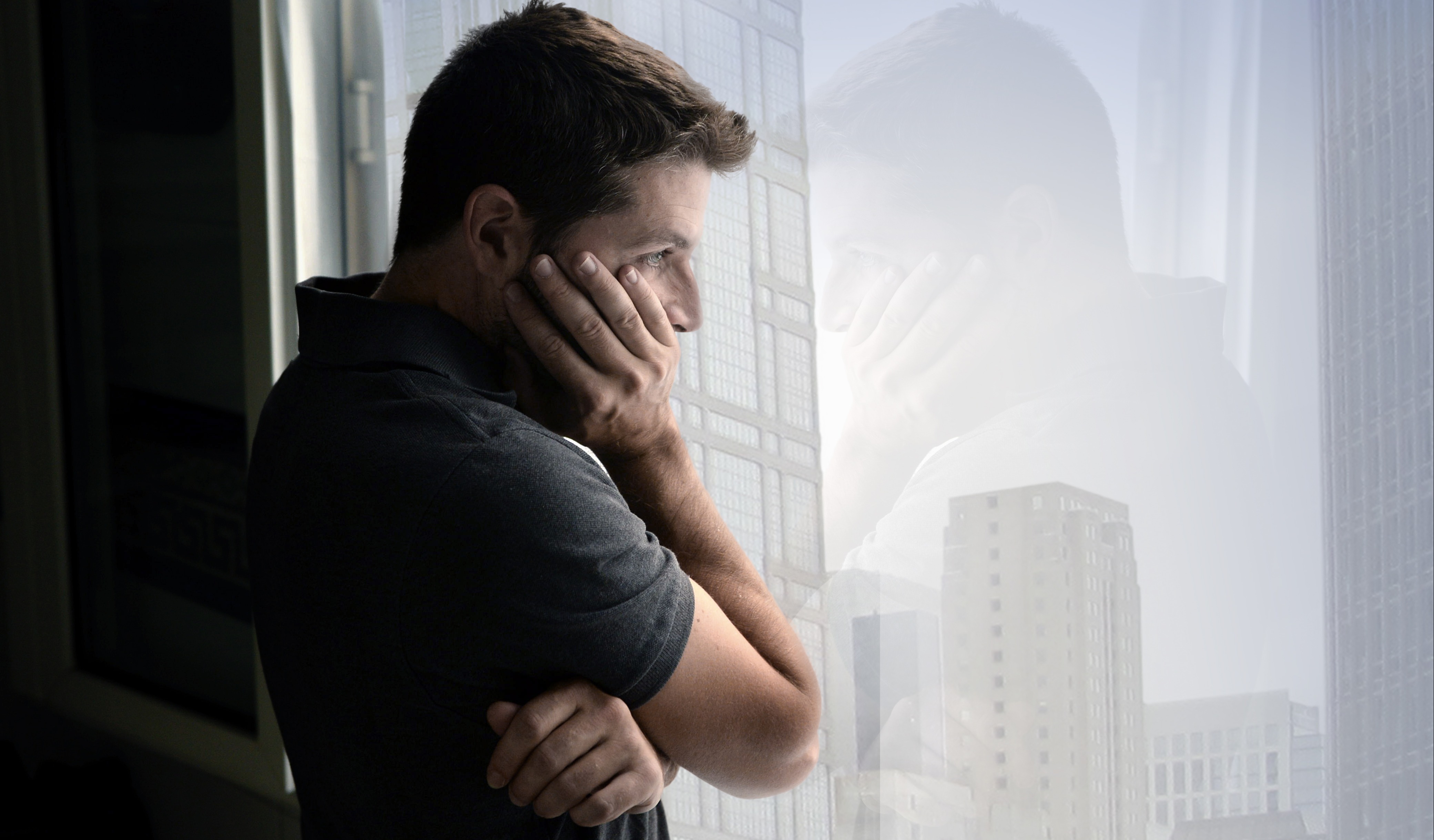 Man solemnly staring out of a window 