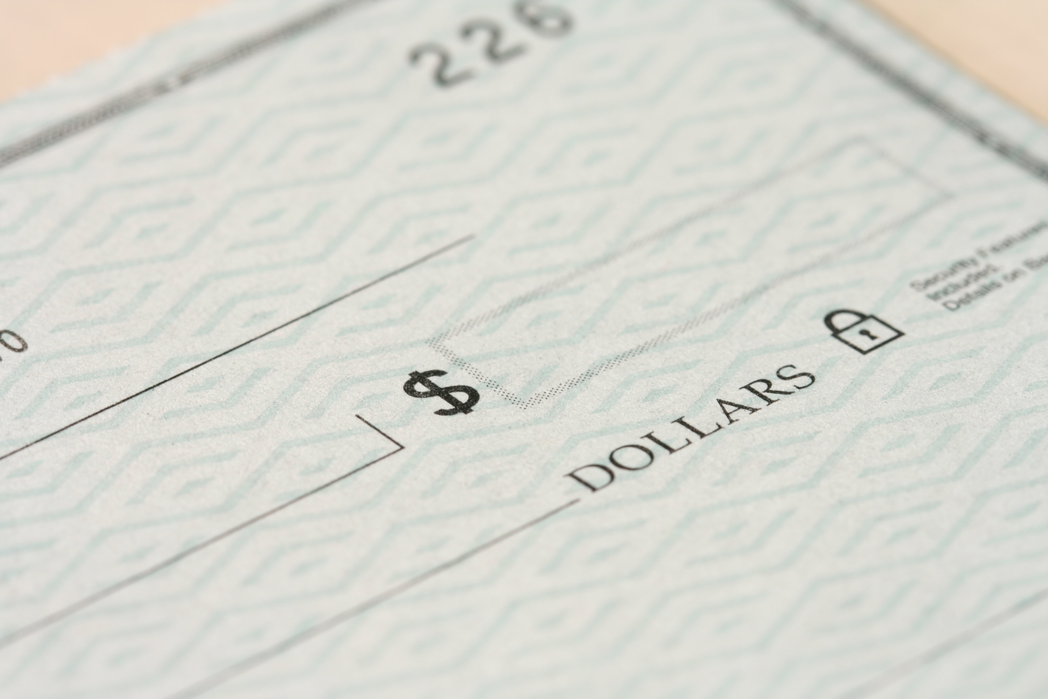 A close up picture of a check showing the dollar amount box, the word dollars, and a few check numbers